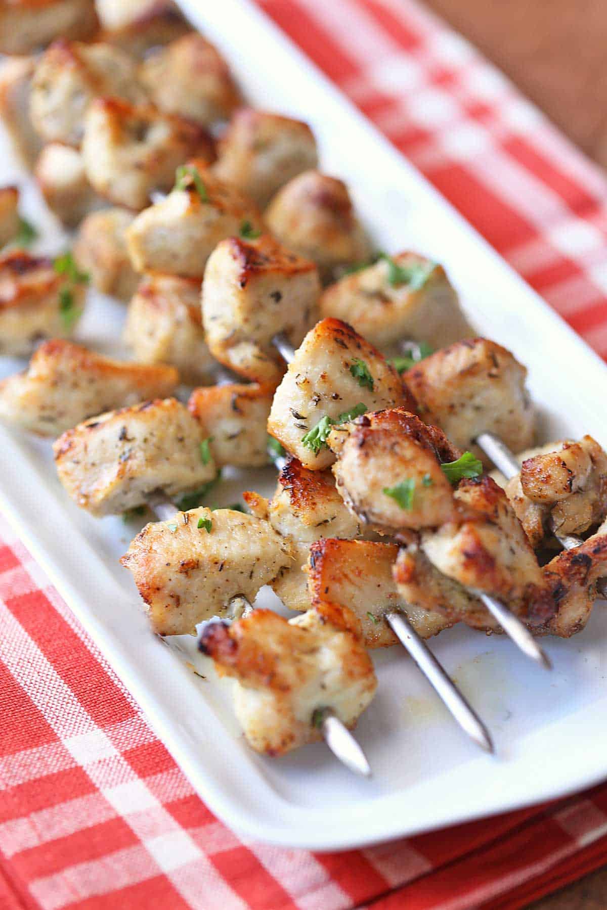 Oven chicken kabobs served on a white plate with a red napkin. 