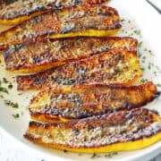 Roasted yellow squash is served on a white plate.