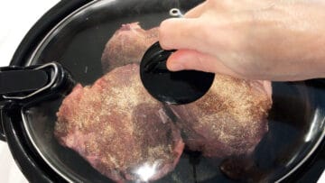 Covering the slow cooker with a lid.