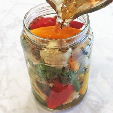 Pouring the brine over the vegetables in the jar.