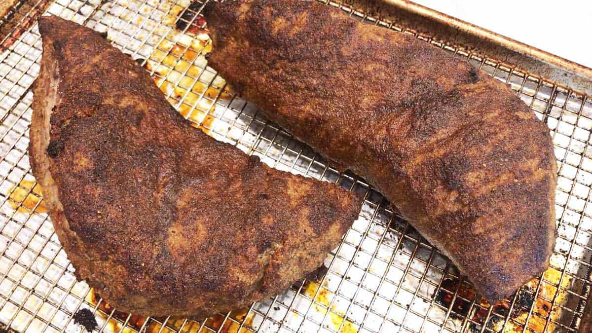 Two fully cooked tri-tip roasts in a pan.