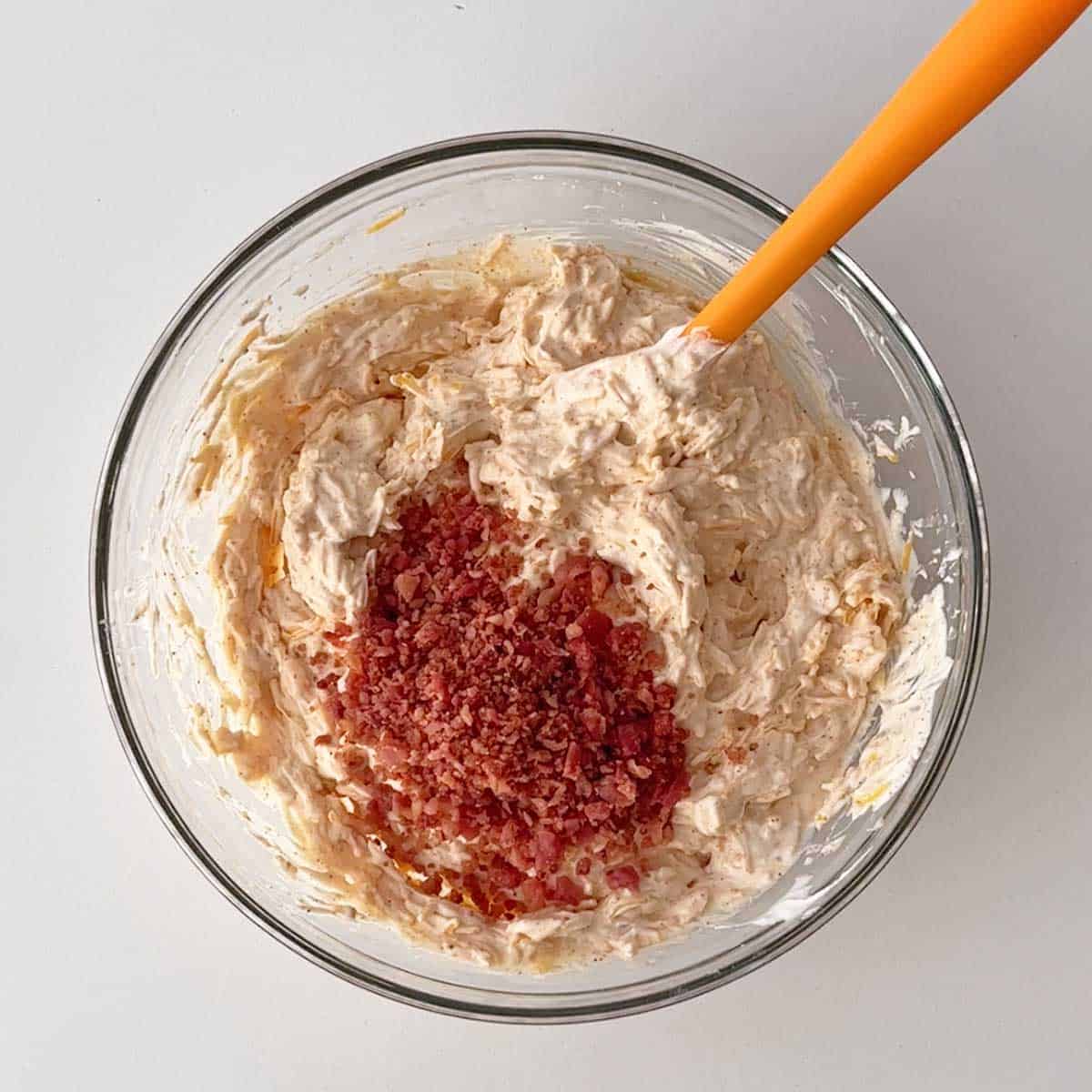 Adding bacon bits to cream cheese dip.
