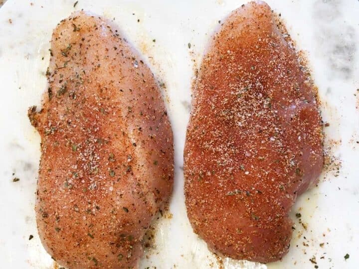 Seasoning the chicken breasts.