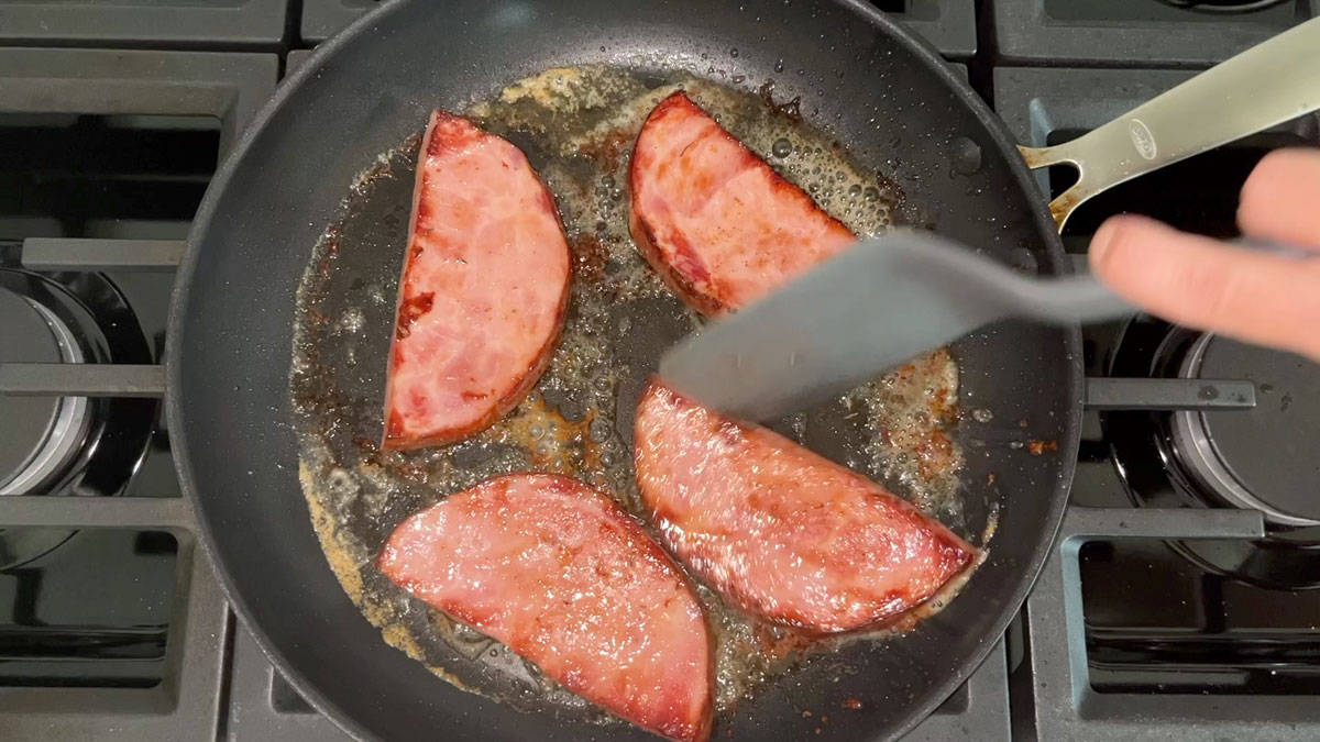 Flipping ham steak in the skillet.