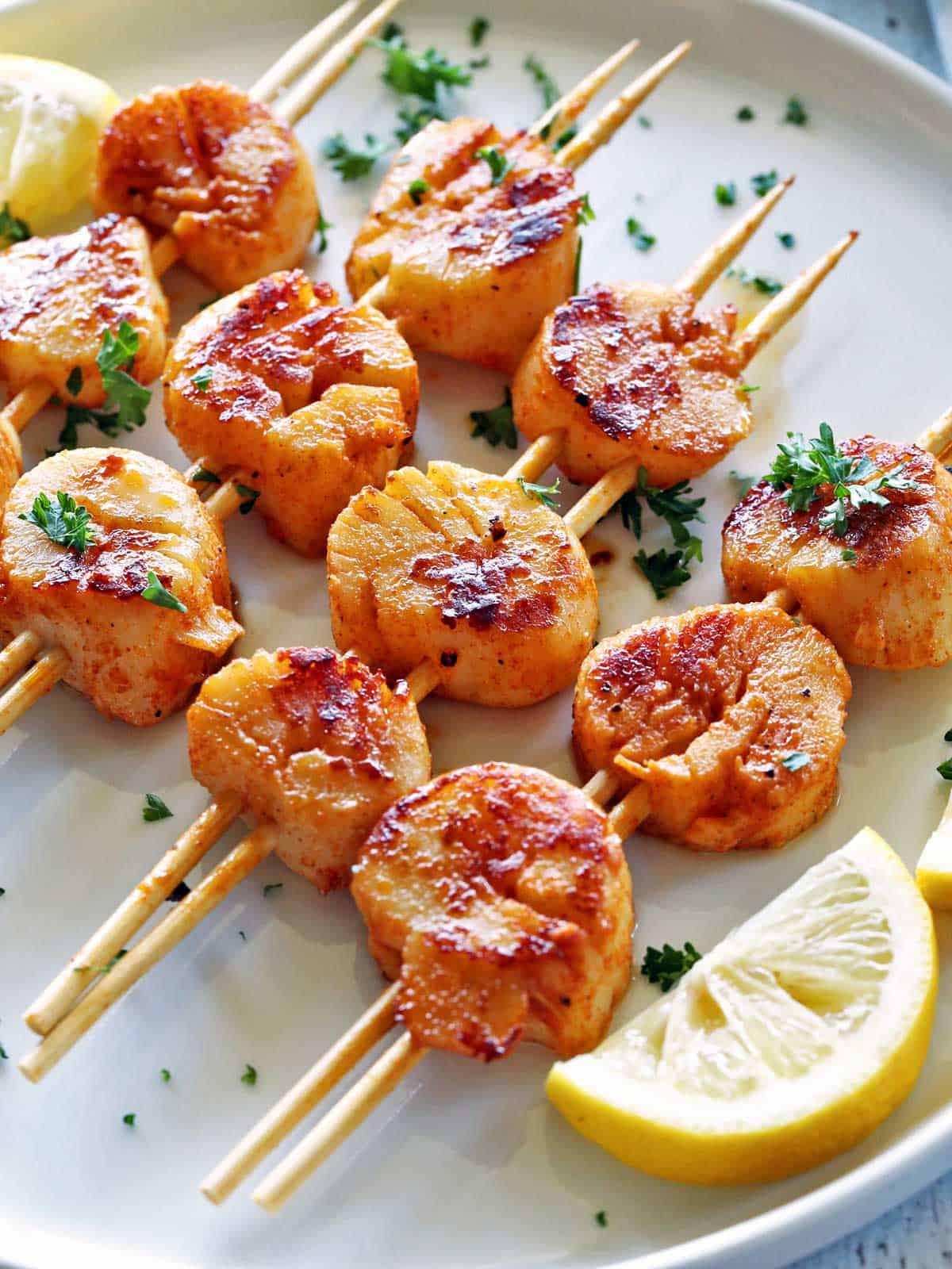 Grilled scallops are served with lemon slices.