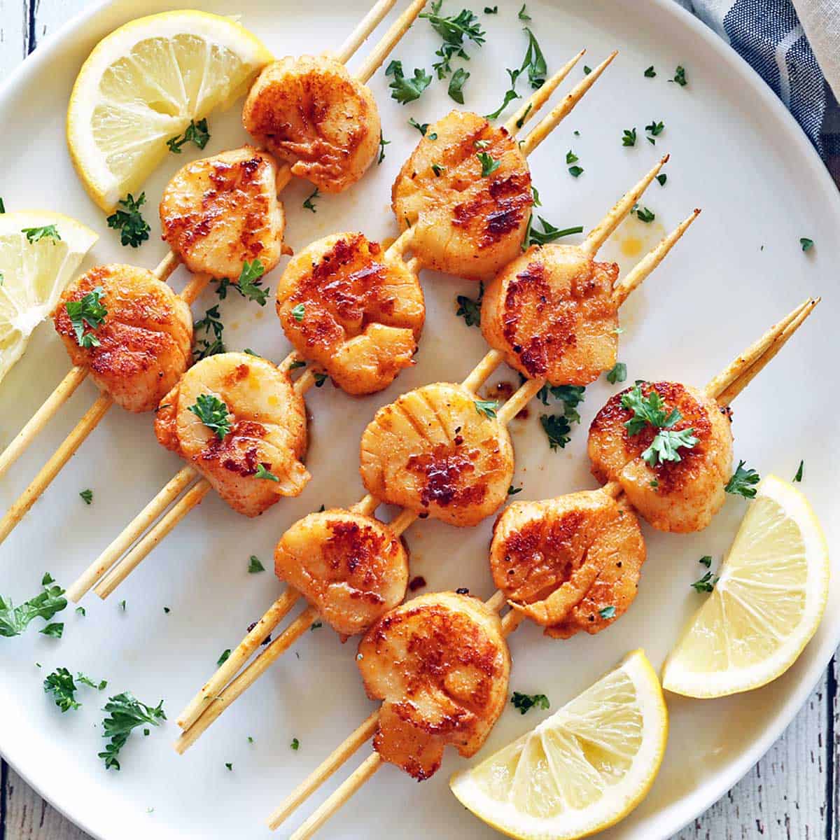 Grilled scallops are served with lemon slices.