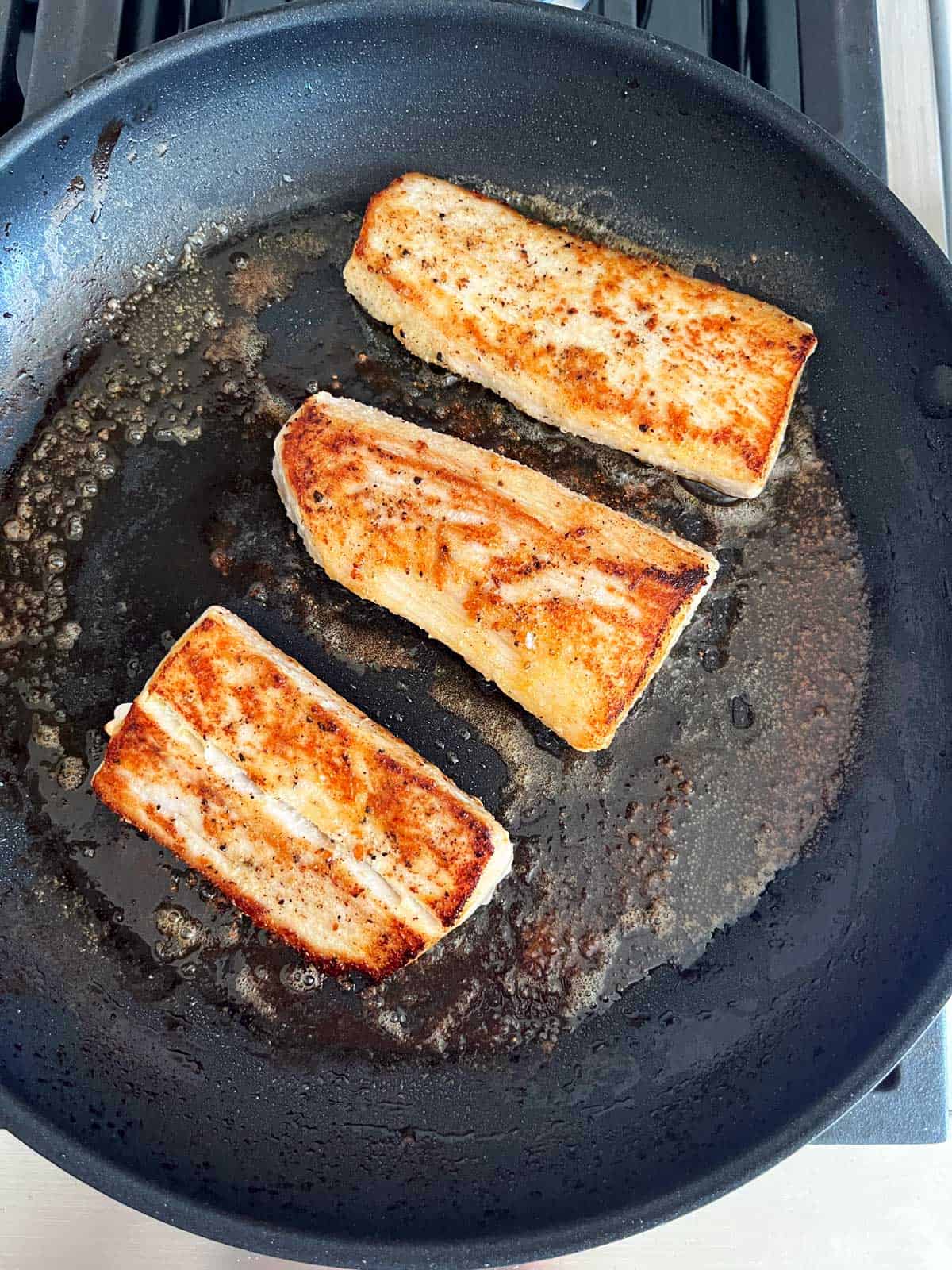 Pan-fried mahi mahi in a skillet.