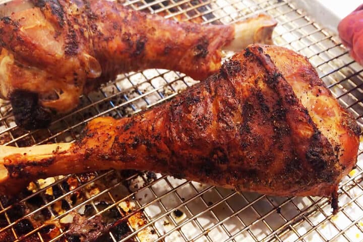 Fully cooked turkey legs on a baking sheet.