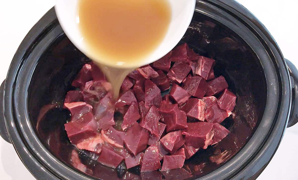 Adding broth to slow cooker.