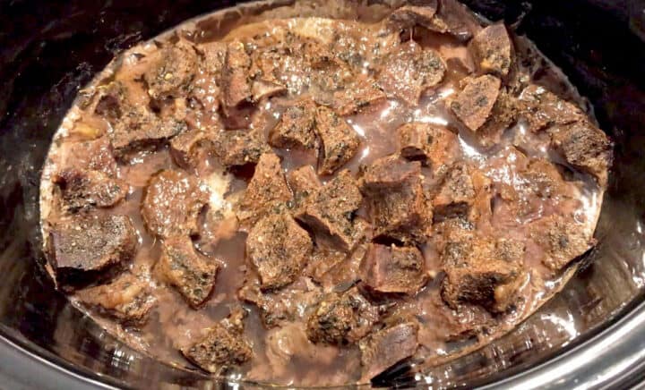 The beef heart is fully cooked in the slow cooker pan.