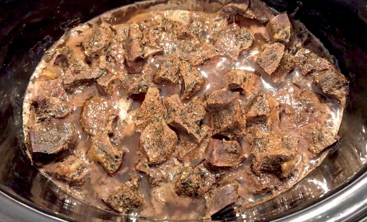 The beef heart is fully cooked in the slow cooker pan.