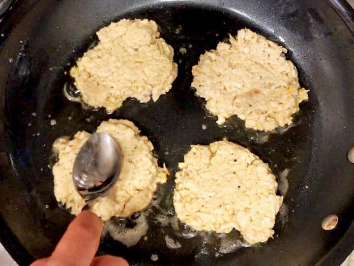 Flattening chicken patties in the skillet.