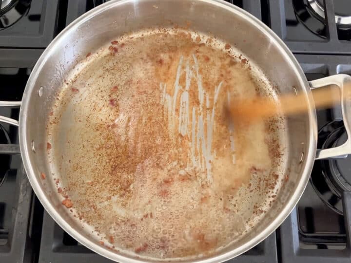 Deglazing the skillet with a wooden spoon.