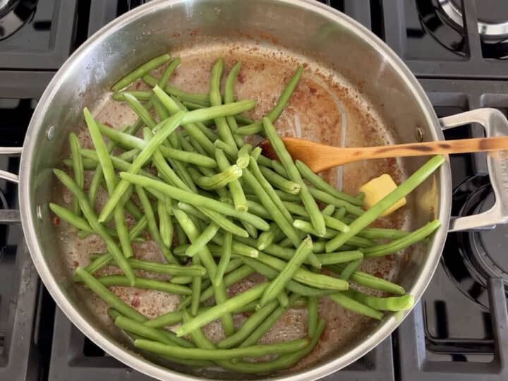 Adding the green beans to the skillet.