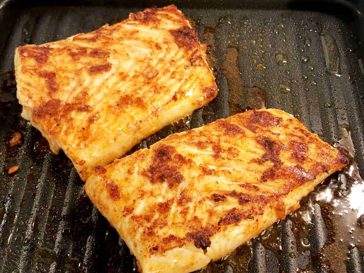 Two fillets perfectly grilled halibut in a grill pan.