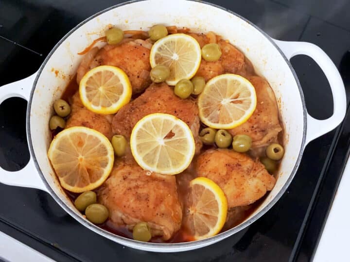 Adding lemon slices and olives to the saucepan.
