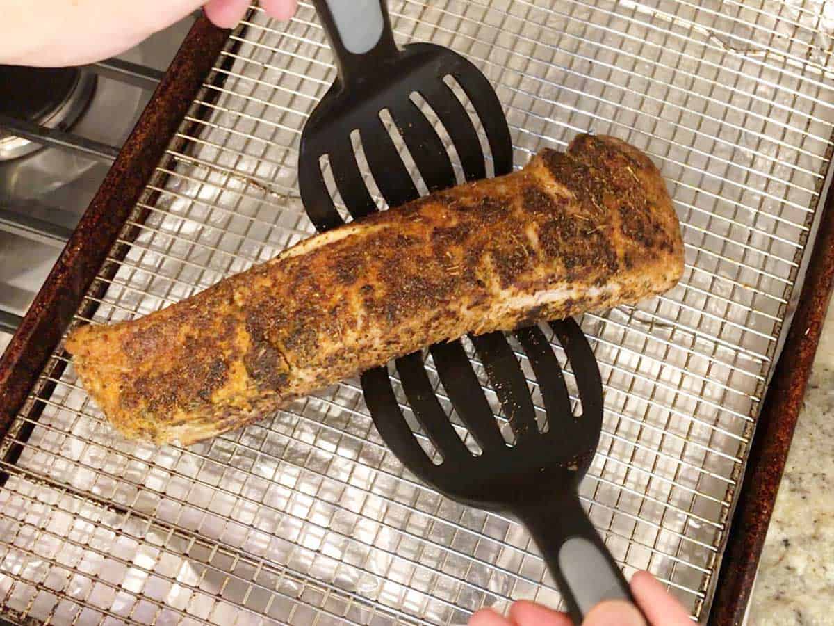 Placing pork tenderloin on a baking sheet. 