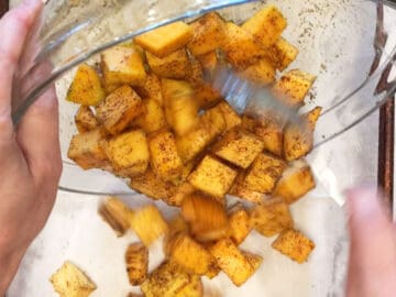 Transferring the butternut squash cubes to the baking sheet.