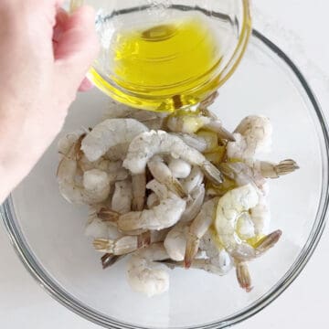 Adding olive oil to the shrimp.
