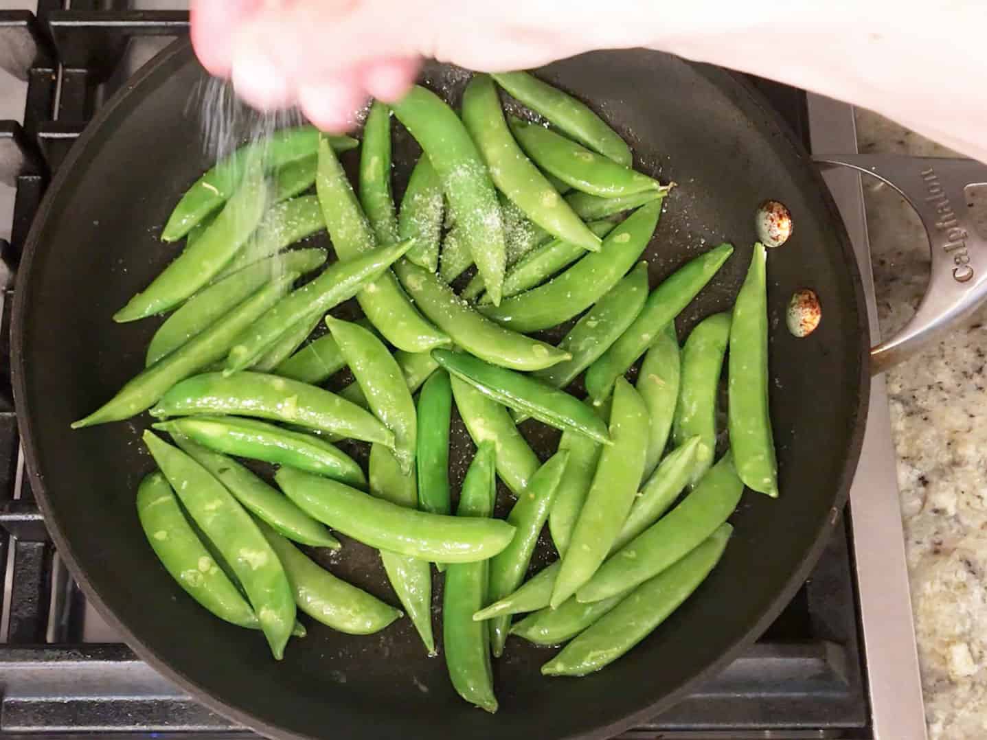 Seasoning sugar snap peas with salt.
