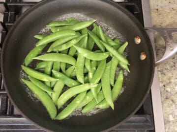 Adding the snap peas to the skillet.