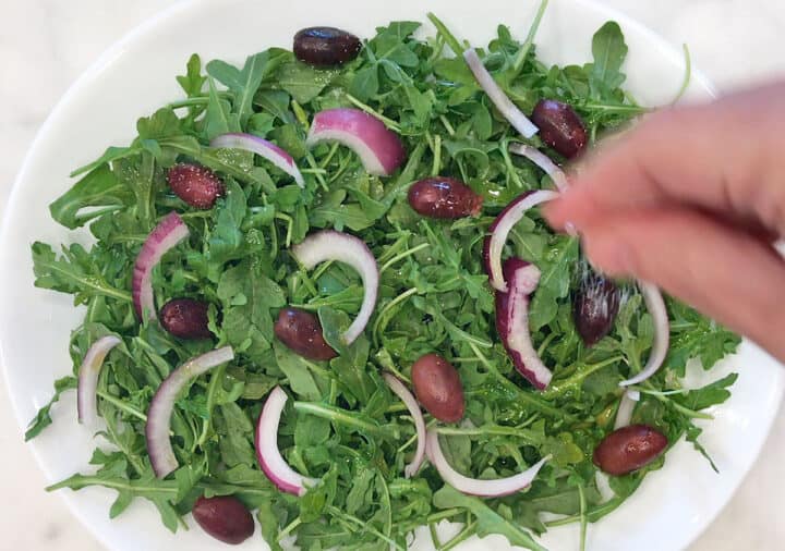 Seasoning the salad with salt.