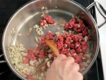 Cooking ground beef and onions in a skillet.