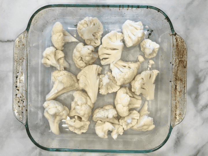 Raw cauliflower florets in a baking dish.