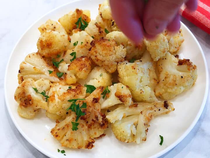 Garnishing roasted cauliflower with parsley.