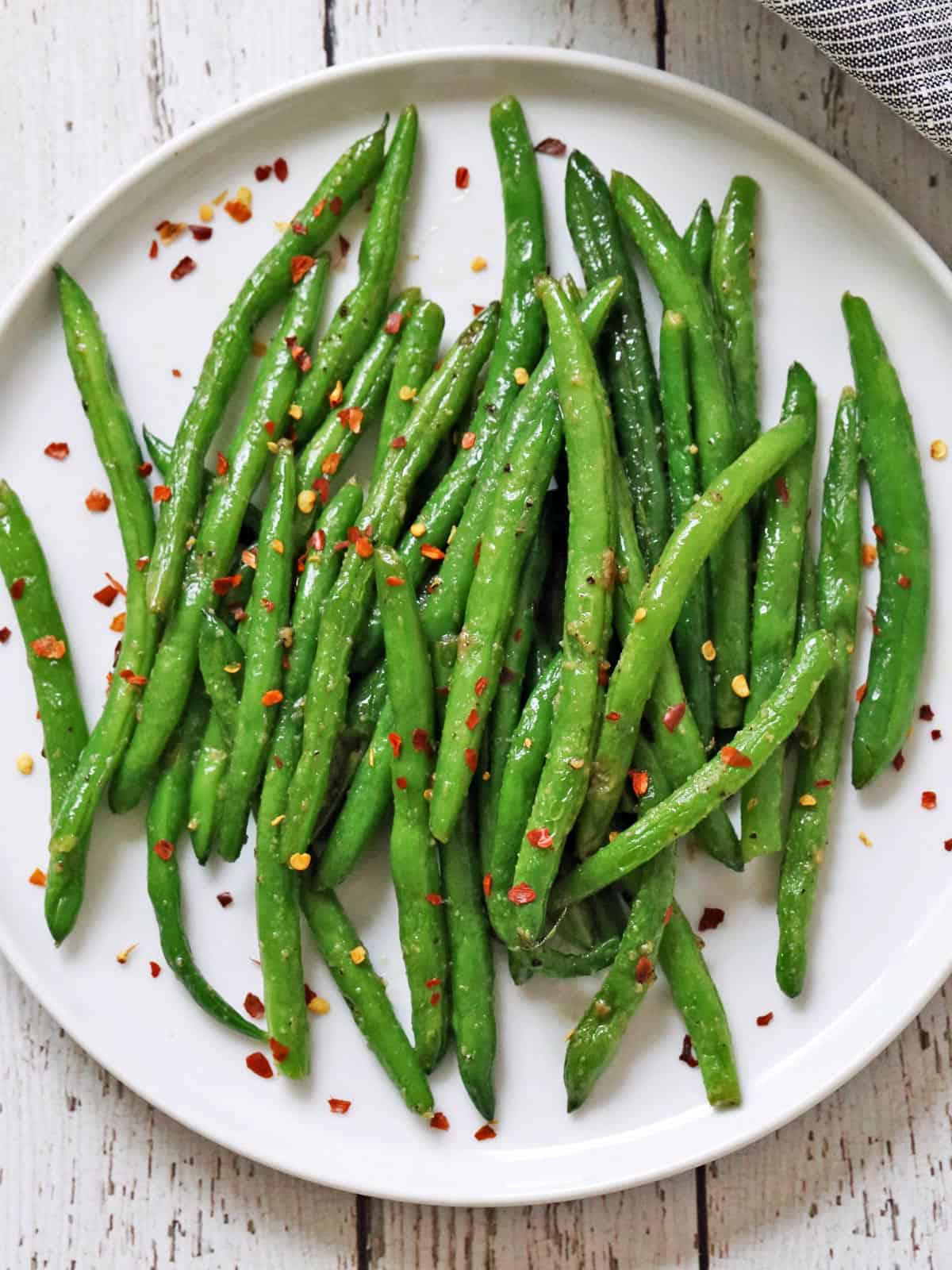 Sauteed green beans are topped with red pepper flakes.