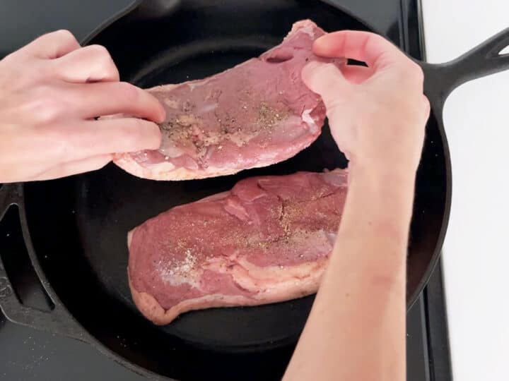 Placing the duck breast in the skillet.