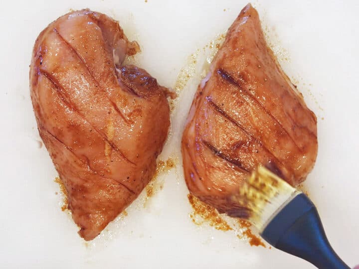 Brushing the chicken with the marinade.