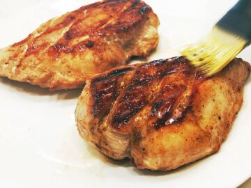 Brushing the grilled chicken with the remaining marinade.