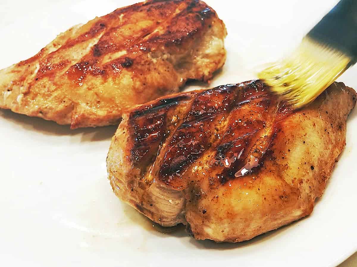 Brushing the grilled chicken with the remaining marinade.