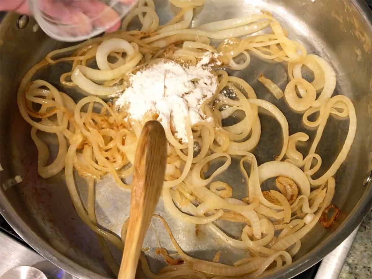 Adding flour to the onions in the skillet.