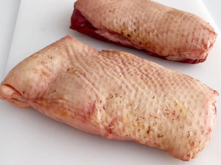 Two raw duck breasts on a cutting board.