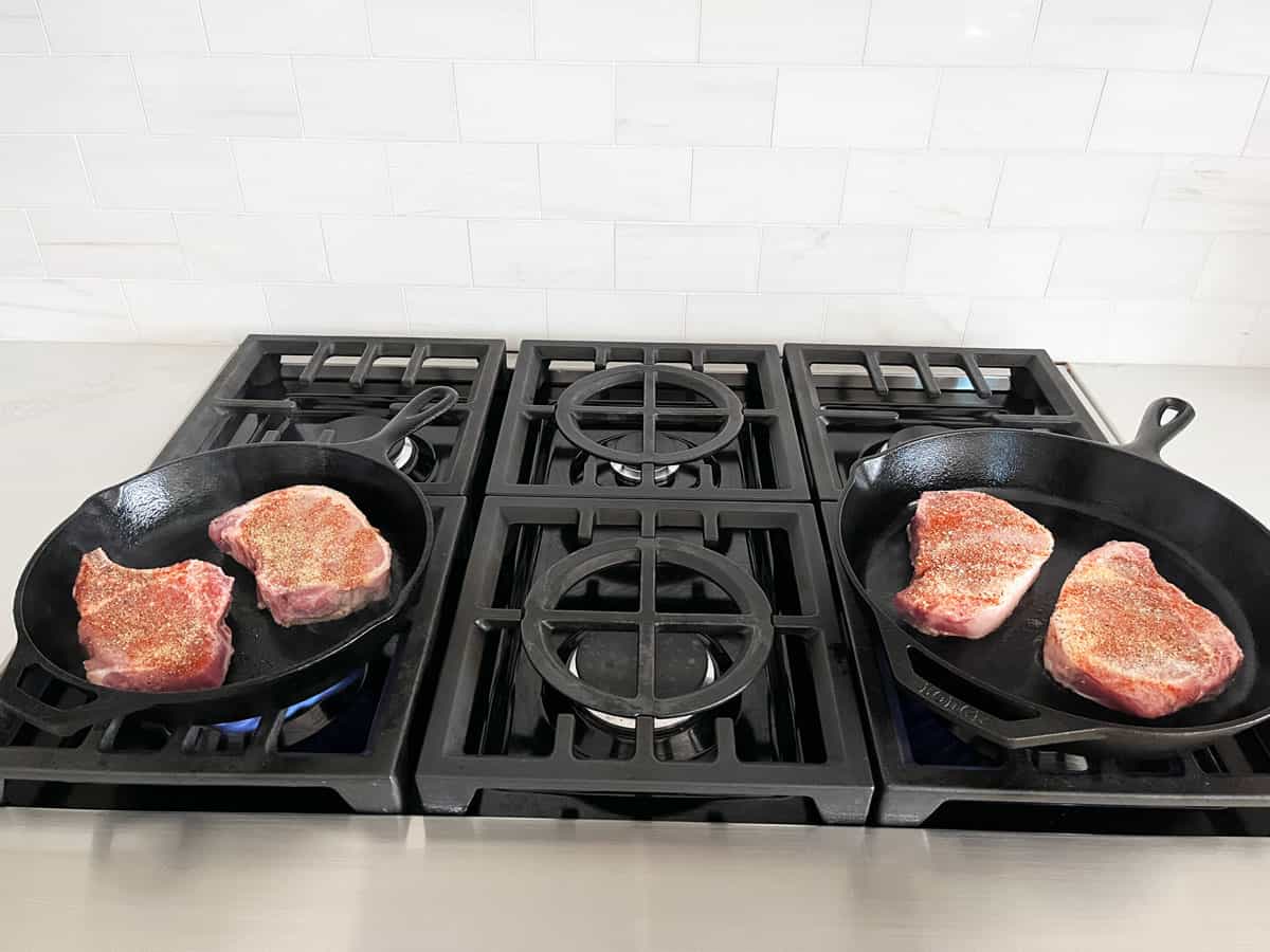 Cooking four pork chops in two separate skillets.