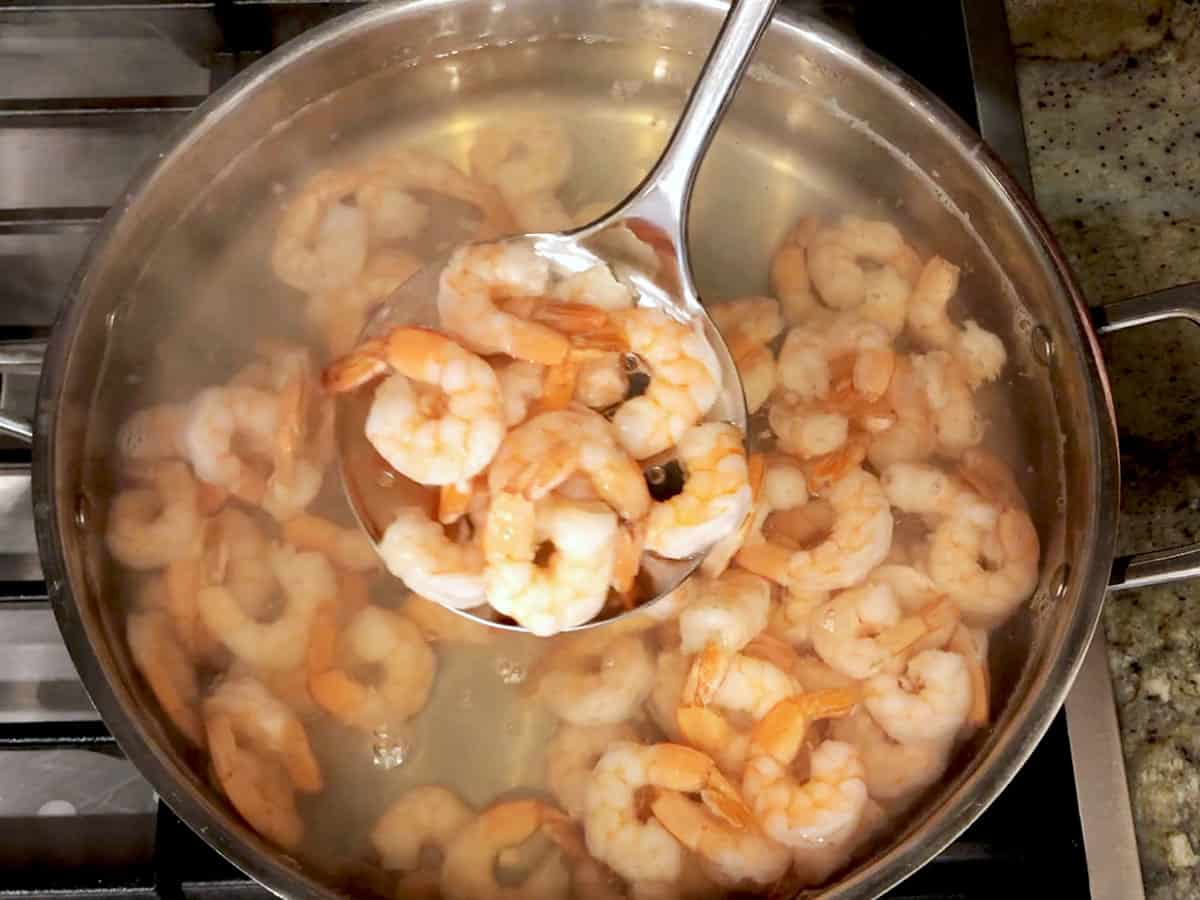 Removing the shrimp from the water with a slotted spoon.