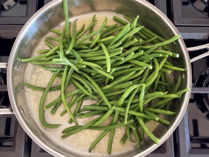 Adding the haricot verts to the melted butter in the skillet.