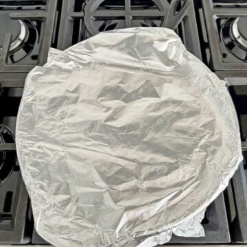 London broil is resting in the skillet, covered in foil.