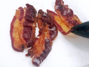 Placing the cooked bacon on paper towels.