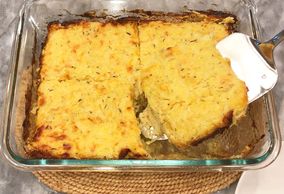 Lifting a slice of casserole out of the pan.