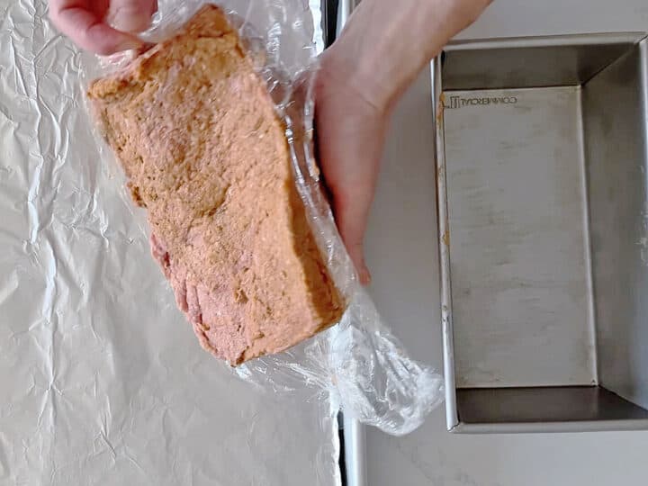 Inverting the shaped meatloaf onto the baking sheet.