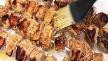 Brushing the grilled skewers with more marinade.