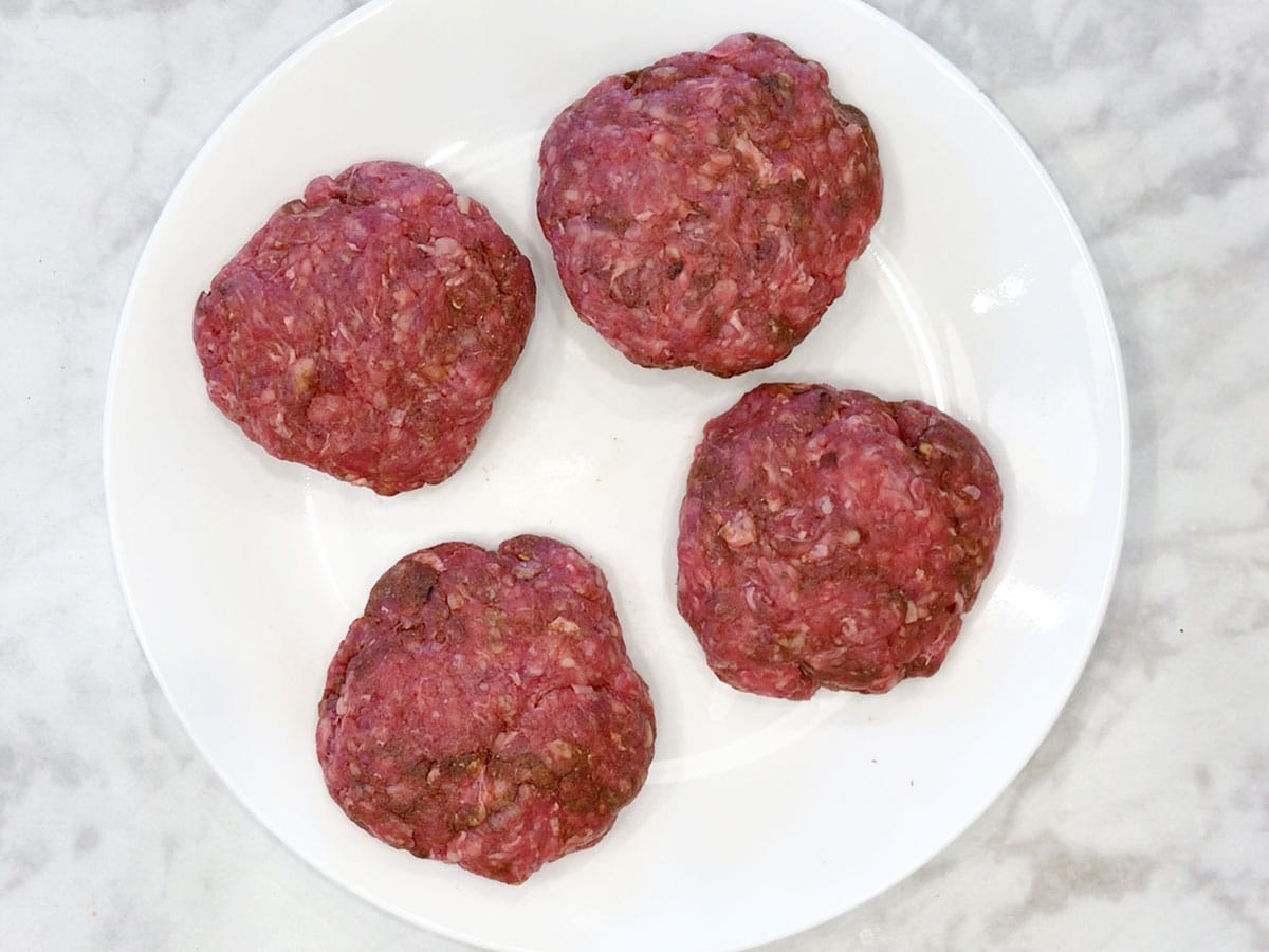Four shaped beef sausages on a plate.