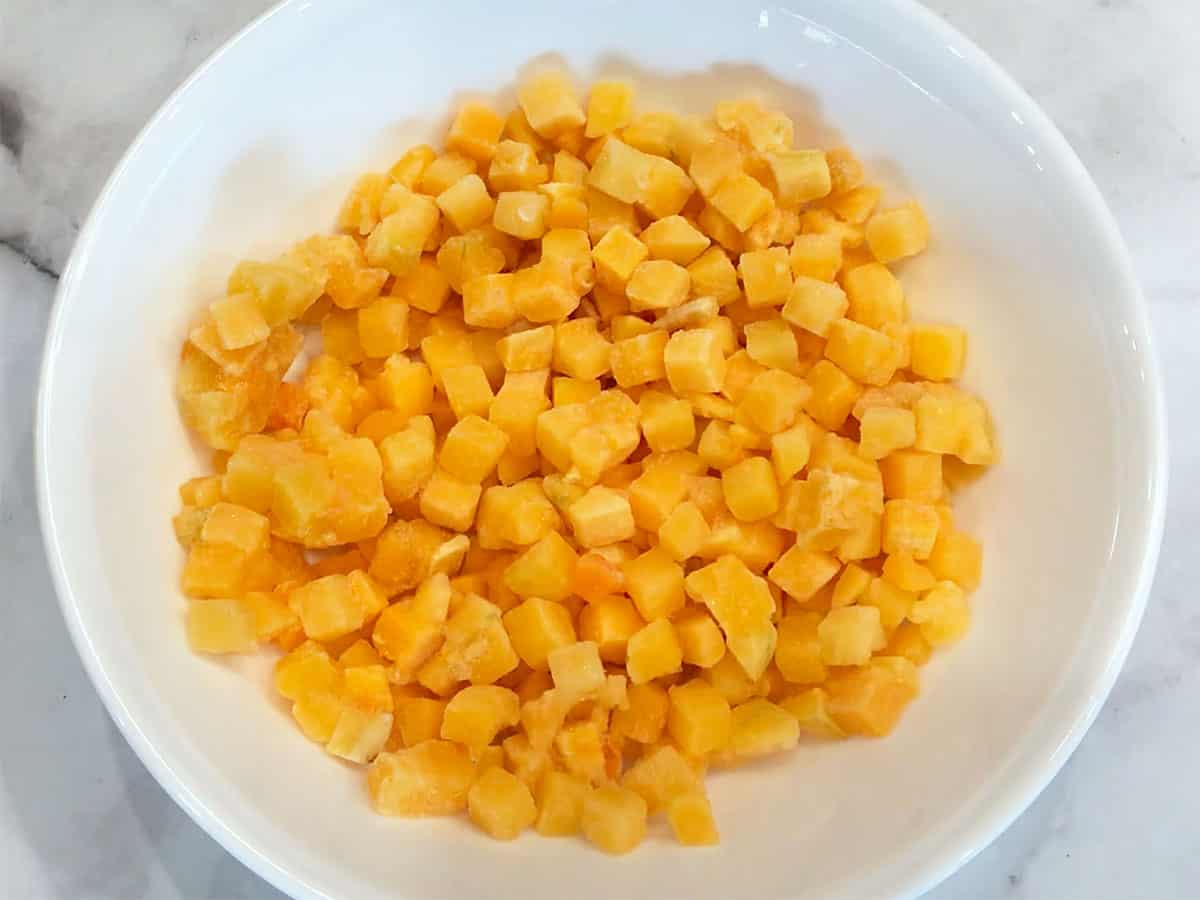Frozen butternut squash cubes in a microwave-safe bowl.