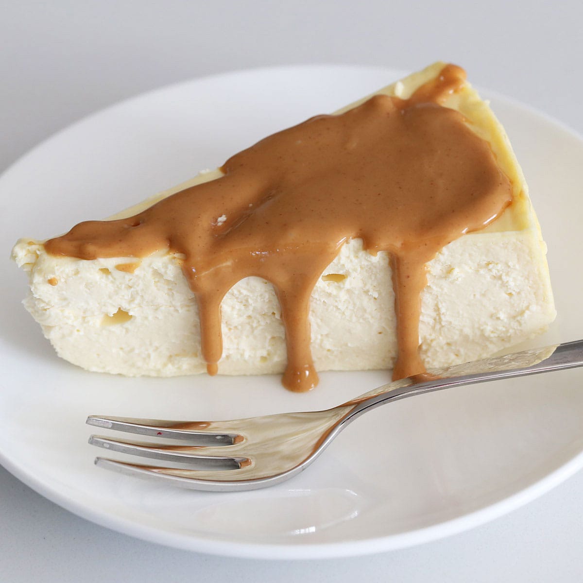 A slice of keto cheesecake topped with melted peanut butter.