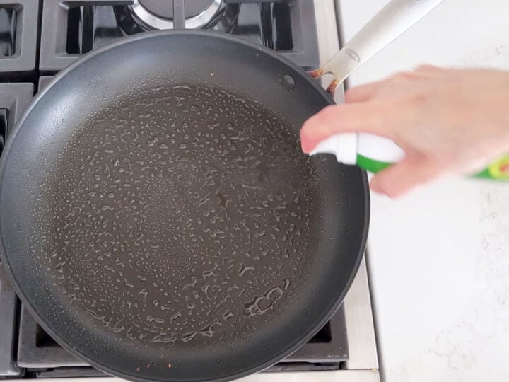 Spraying the skillet with oil.