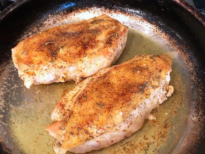 Butter was spooned on top of the chicken pieces in the skillet.