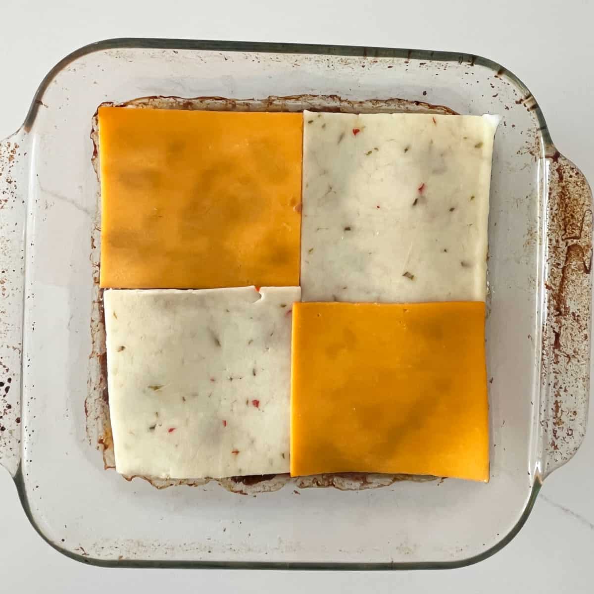 Topping the beef mixture with cheese slices.